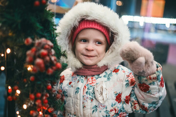 portrait of a beautiful little girl in a winter white jacket near the Christmas decor