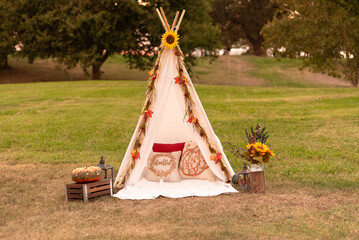 Autumn-themed boho teepee setup with pillows, pumpkins, and sunflowers.