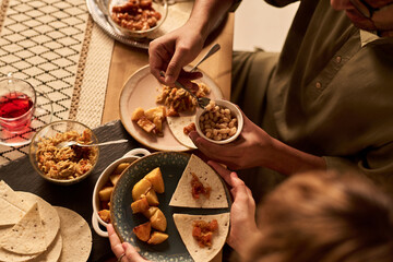Friends enjoying a meal featuring tortillas, beans, and other traditional Hispanic dishes, sitting...