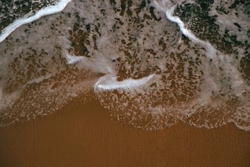 Textured Background. Sea foam splashed on the shore. Top view. Abstract composition. Sand. Waves. Postcard. Cover. Picture. Wallpaper. Close-up