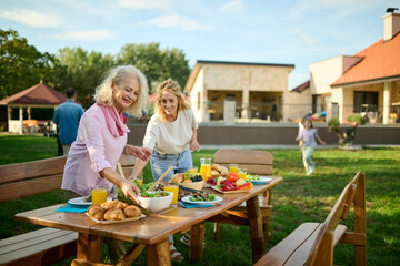 Happy family arranging food on table for outdoor garden party