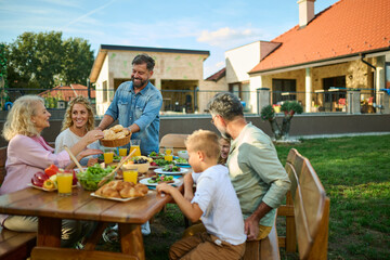 Happy family having lunch together in the backyard of their home
