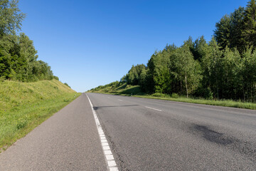 an empty straight paved road against a blue sky background