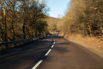 Fototapeta premium Motion blur view of a winding road through a forest 