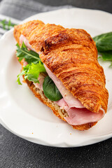 Croissant sandwich ham, cheese, green leaf salad delicious gourmet food background on the table rustic food top view copy space