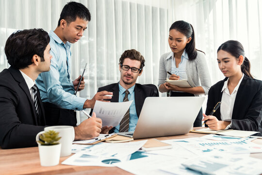 Diverse group of business analyst team analyzing financial data report paper on office table. Chart and graph dashboard by business intelligence analysis for strategic marketing planning Meticulous