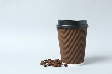 Paper cup with plastic lid with coffee beans on light background. Coffee to go