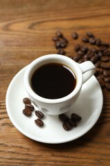 Cup of coffee and fresh coffee beans on wooden background