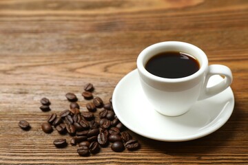 Cup of coffee and fresh coffee beans on wooden background