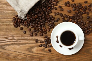 Cup of coffee and fresh coffee beans on wooden background