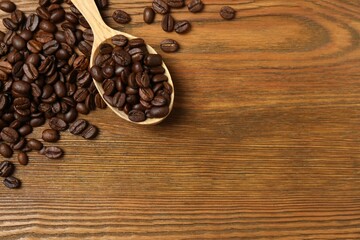 Fresh coffee beans in a wooden spoon on a wooden background