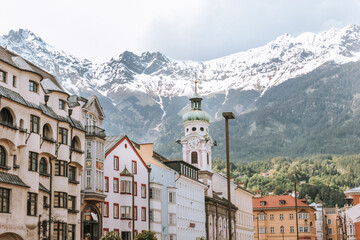 Naklejka premium Stunning view of Innsbruck, Austria, where snow-capped mountains meet colorful architecture in a picturesque alpine setting.