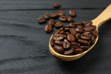 Fresh coffee beans in a wooden spoon on a wooden background
