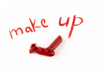 Artistic Representation of Makeup: A Broken Lipstick with Red Shavings and the Words 'Make Up' in Bright Red Script on a Clean White Background