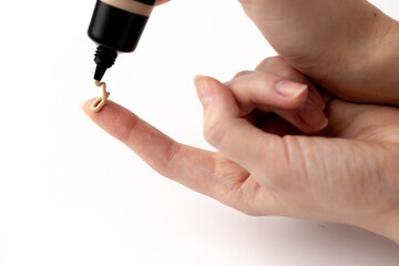 Applying Foundation on Finger: A Close-Up of Liquid Makeup Being Dispensed from a Bottle for...
