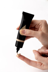 Exploring the Art of Beauty: A Hand Holding a Foundation Tube with a Creamy Texture on a Finger for...