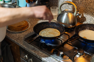 Traditional baking of pancakes for Shrovetide. The process of making delicious pancakes.