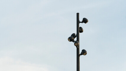 Fototapeta premium Minimalist View of a Tall Black Street Light Pole with Multiple Spotlights Against a Clear Sky
