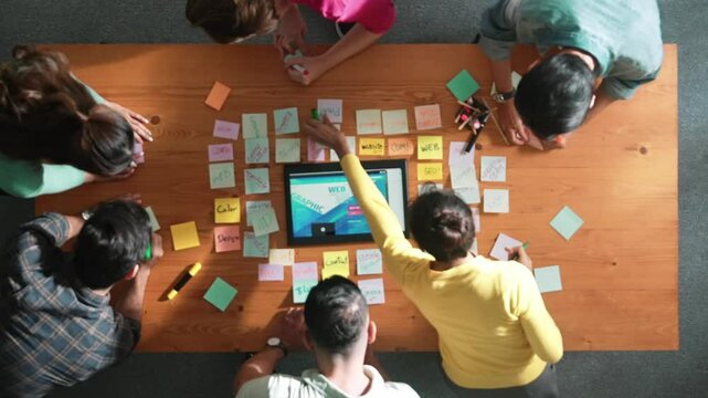 Time lapse of programmer brainstorming and planning about web design while looking at tablet wireframe prototype. Aerial view of skilled developer team talking about digital application. Symposium.