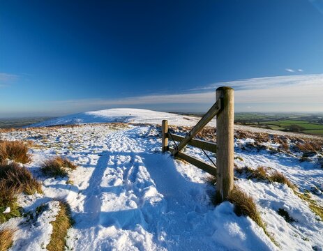 a stile on ditchling beacon on a january day with snow on the ground but a blue sky overhead