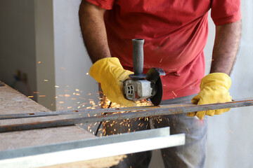 Industrial worker cutting iron with a grinder that produces sparks. Blacksmith in his workshop	
