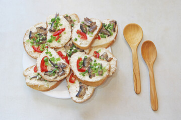 toasts with sprats and green onions on plate. Sandwiches for breakfast