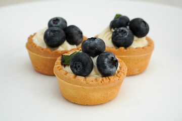 Delicious blueberry cupcakes with white chocolate cream on a white plate on a white background. Beautiful cake decoration.