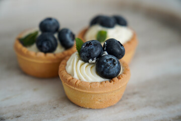 Delicious blueberry cupcakes with white chocolate cream on a ceramic plate. Beautiful cake decoration.