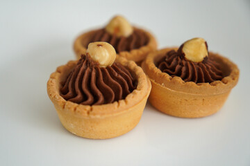 Delicious chocolate cupcakes with hazelnut on top on a white plate on a white background. Beautiful cake decoration.