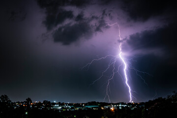 A dramatic photograph capturing powerful lightning strikes illuminating the dark sky. The jagged...