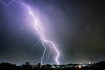 A dramatic photograph capturing powerful lightning strikes illuminating the dark sky. The jagged...