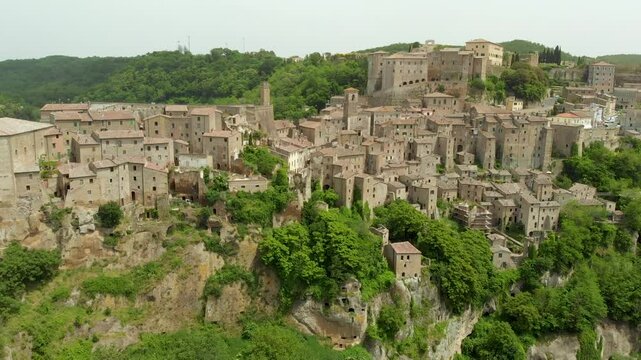 Aerial summer afternoon view of Sorano. Rooftops of an ancient medieval hill town hanging from a tuff stone over the Lente River. Etruscan heritage. Province Grosseto, Tuscany, Italy.