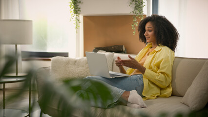 African American girl relax on couch at home apartment ethnic young smiling woman talking video...