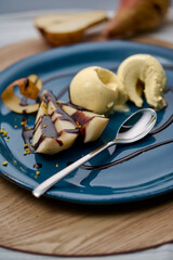 Pear with bourbon vanilla ice cream with chocolate sauce on a blue plate