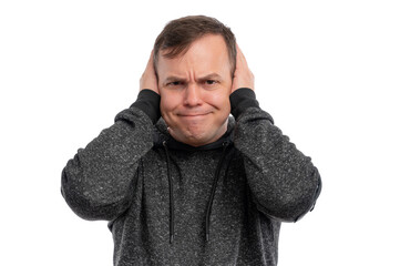 A man in a gray hoodie covering his ears, showing a distressed expression against a white...