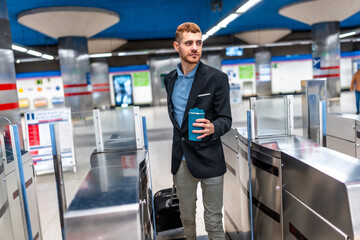 Businessman passing through subway turnstile holding reusable coffee cup