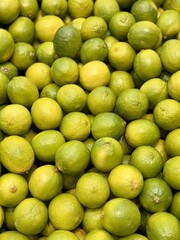 Ripe fresh green limes on the shelf of a fruit supermarket are displayed for sale