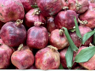 A lot of ripe red pomegranates on a market counter for sale on sale in vegetable stand display at supermarket show organic food, vegetarian food, healthy food