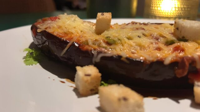 bake eggplant with cheese Halves of purple eggplants cut lengthwise baked with minced meat, grated cheese and tomato slices on a baking tray on kitchen table