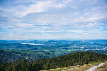 A breathtaking view of the foothills of Mount Pilatus near Lucerne, Switzerland. Green forests, yellow rapeseed fields, and a shimmering lake create a stunning landscape in Central Switzerland.