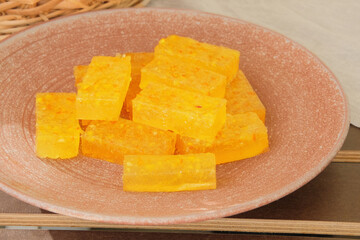 Marmalade in a plate in garden table. Sweet orange dessert for holiday. Homemade fruit candies.
