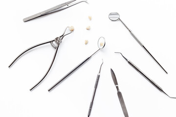 Dental crowns with steel instruments for dental prosthetics, top view. Dentist desk, white background