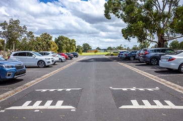 An outdoor parking lot with various parked cars and speed bumps designed to control vehicle speed...