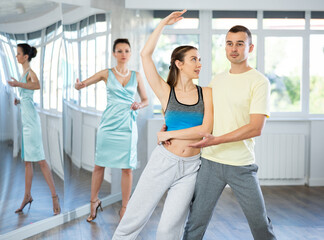 Man and girl take dance lessons from experienced teacher. Couple in sports clothes practices boogie...
