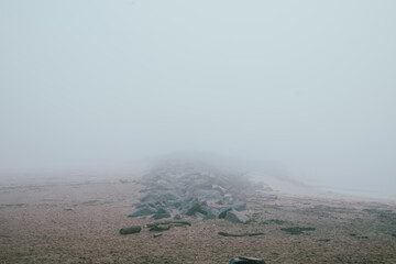 A thick fog blankets a beach, obscuring the distant water.  