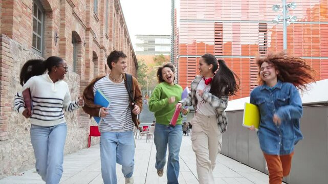 Group of students running happily after class, holding notebooks and backpacks, enjoying friendship, laughter, and energy outdoors on a bright day near modern educational buildings and campus pathways