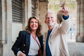 Joyful mature couple exploring a vibrant city, sharing a moment of discovery as they point out interesting sights during their day out together, capturing the essence of travel and companionship.