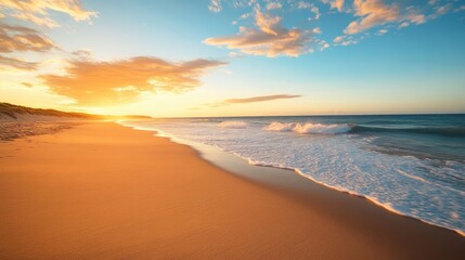 Obraz premium A beautiful golden sandy beach bathed in the warm light of sunset, with long shadows and the peaceful ocean stretching into the distance.