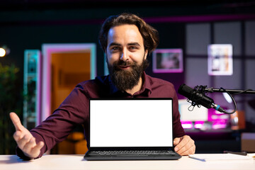 Portrait of cheerful man in studio filming tech tutorial on how to do maintenance on mockup laptop....