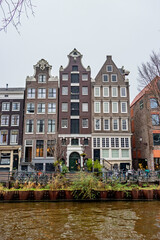 Obraz premium An iconic view of traditional Dutch facades by the canal in Amsterdam, Netherlands. The architecture features gabled roofs and large windows, showcasing the city's historical charm.